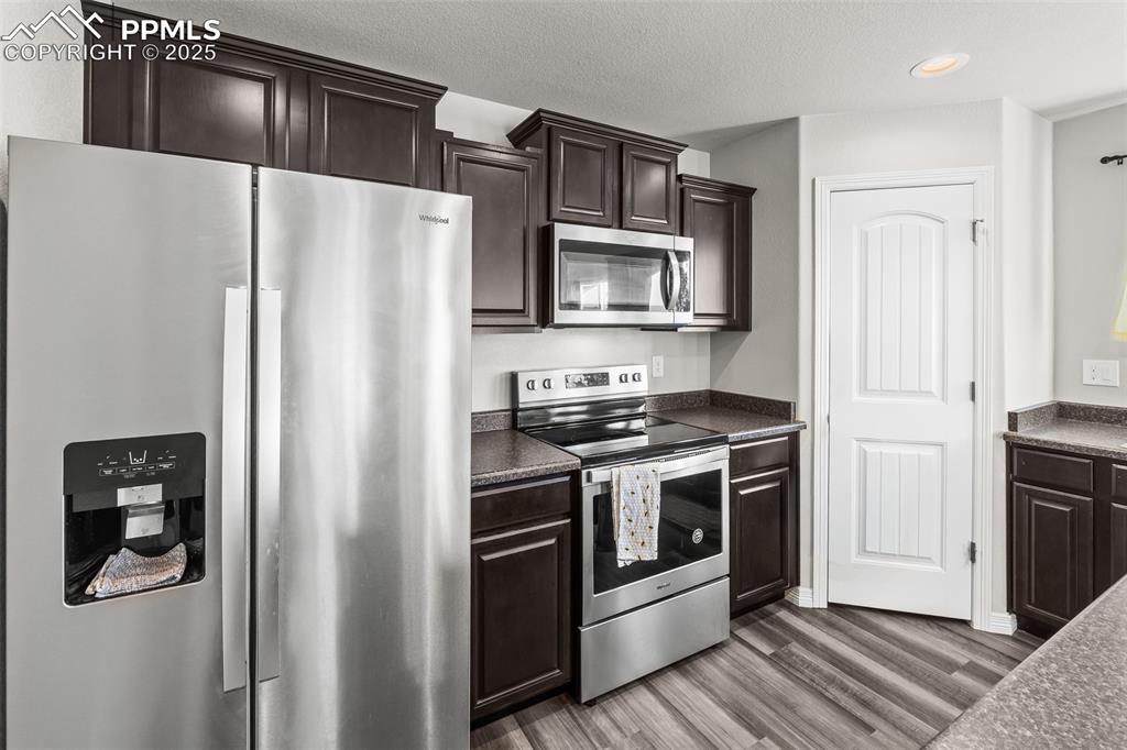 Image 27 of 48: Kitchen featuring appliances with stainless steel finishes, dark wood finis