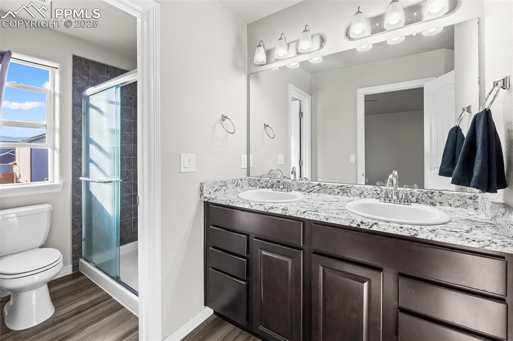 Image 35 of 48: Bathroom with a shower stall, double vanity, and dark wood finished floors