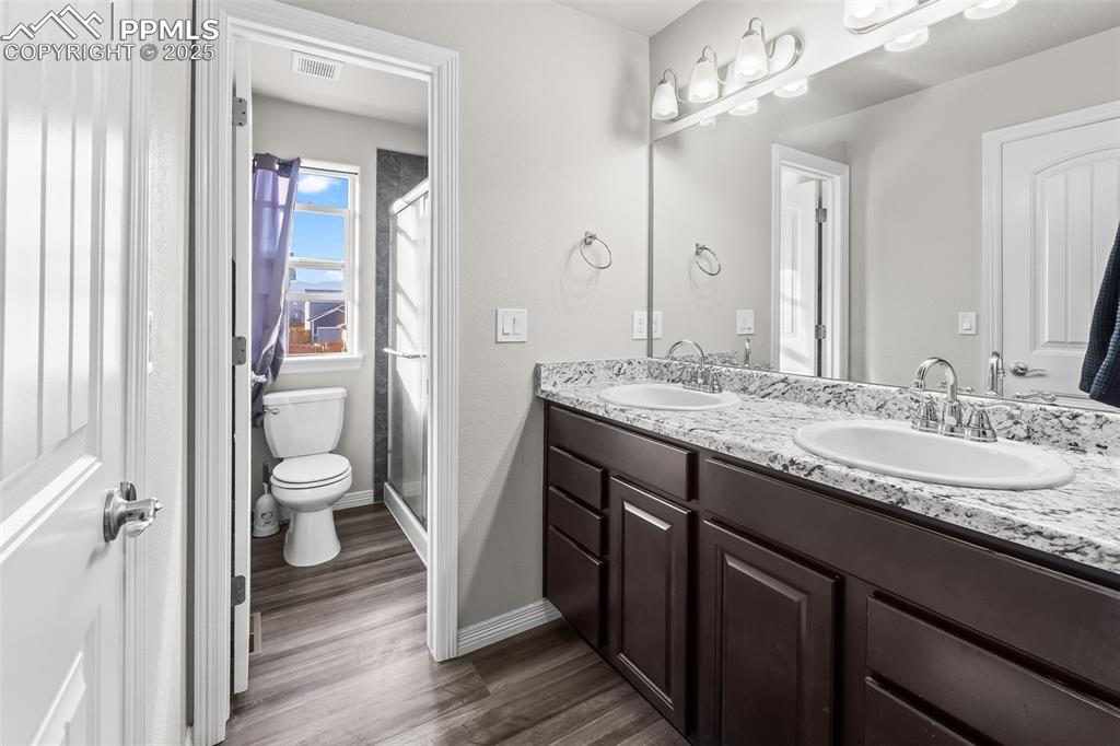 Image 37 of 48: Bathroom with a shower stall, double vanity, and dark wood-style flooring