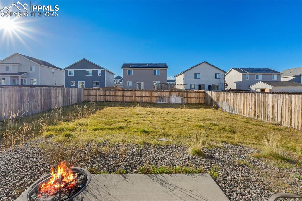 Image 7 of 48: Fenced backyard with a fire pit and a residential view