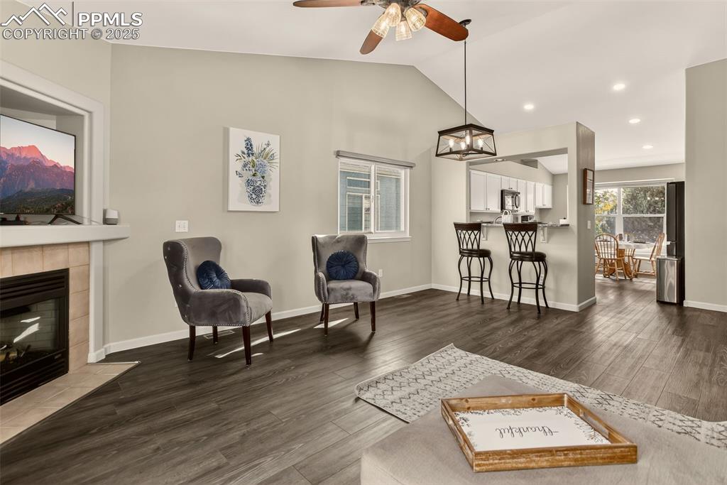 Image 10 of 38: Living area featuring dark wood-style flooring, vaulted ceiling, a tiled fi