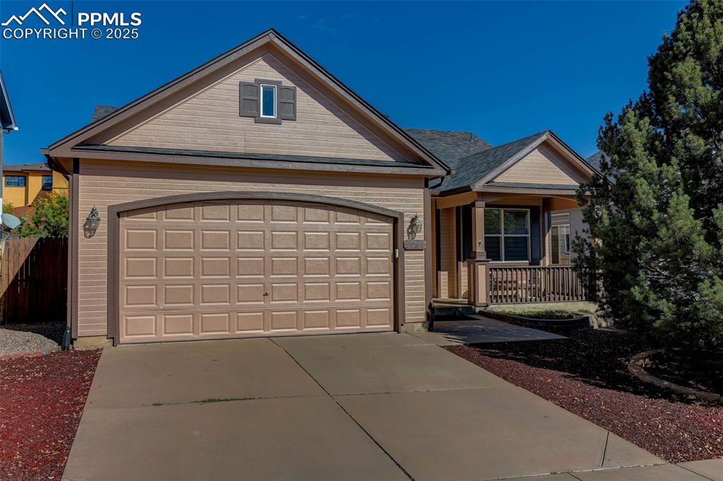 Image 2 of 38: View of front of home featuring concrete driveway, covered porch, and a gar
