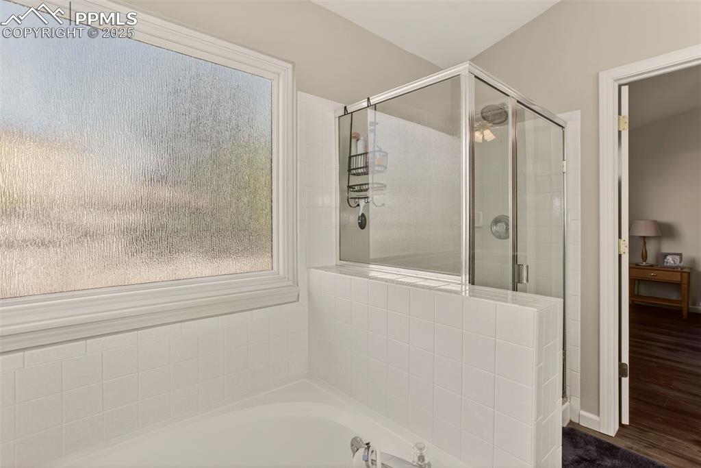 Image 22 of 38: Bathroom featuring a stall shower, a bath, and new LVP