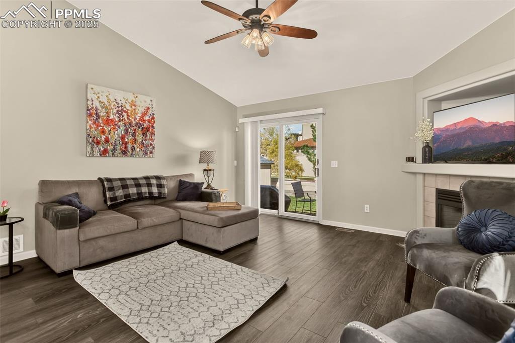Image 9 of 38: Living room with dark wood finished floors, a tile fireplace, ceiling fan,
