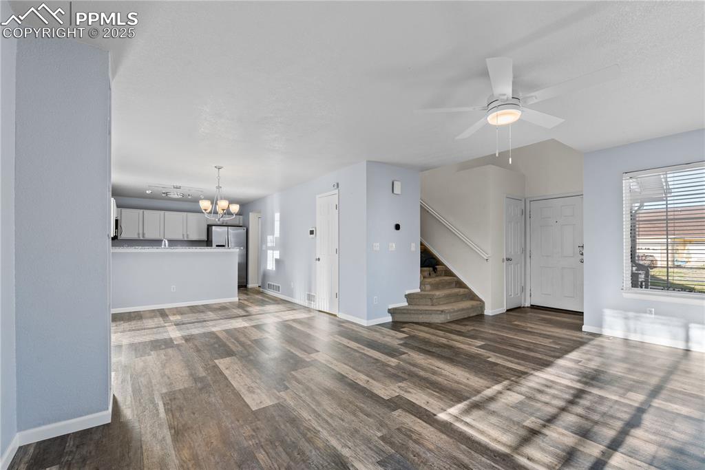 Image 15 of 48: Unfurnished living room with visible vents, baseboards, and wood finished f