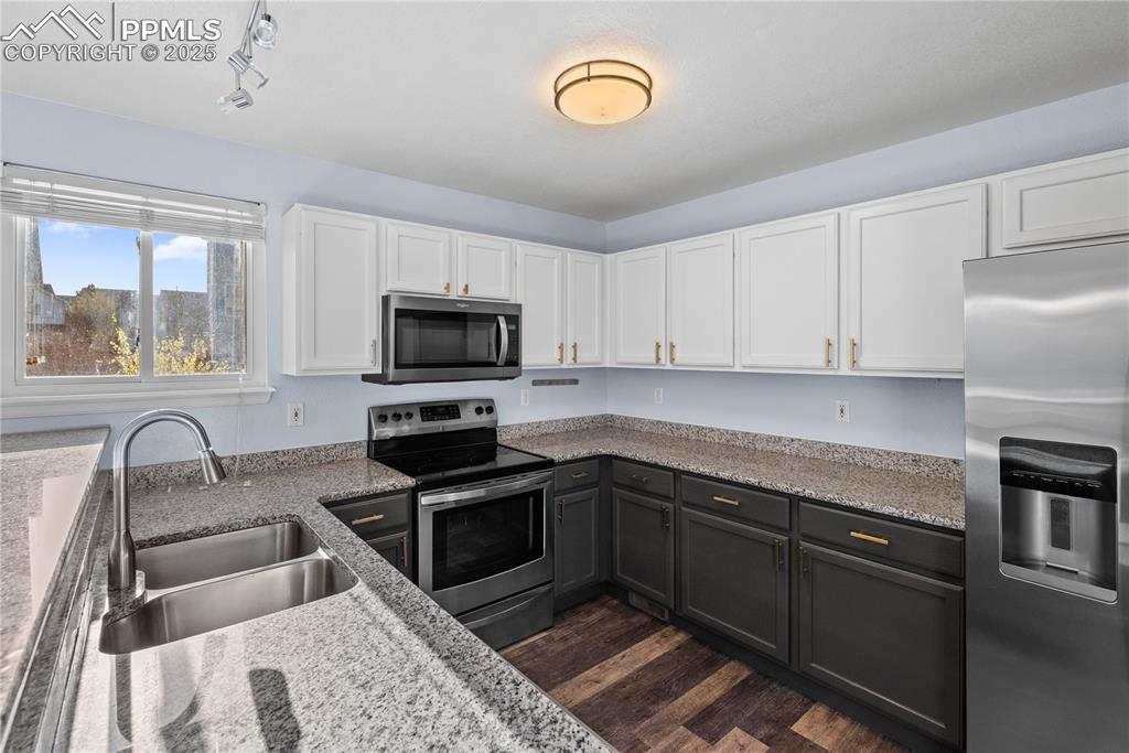 Image 9 of 48: Kitchen featuring white cabinets, a sink, appliances with stainless steel f