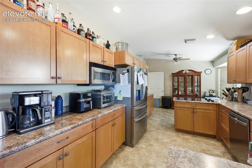 Image 11 of 49: Kitchen featuring wood-finish cabinetry, speckled countertops, and tile flo