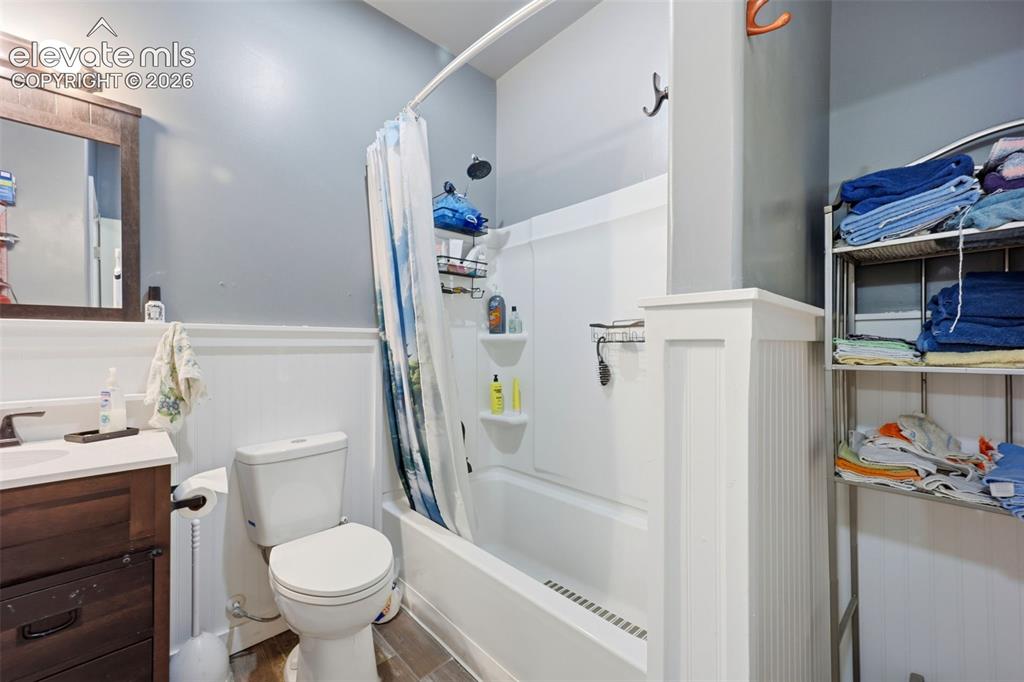 Image 16 of 49: Bathroom featuring a white tub/shower combination, dark wood-finish vanity