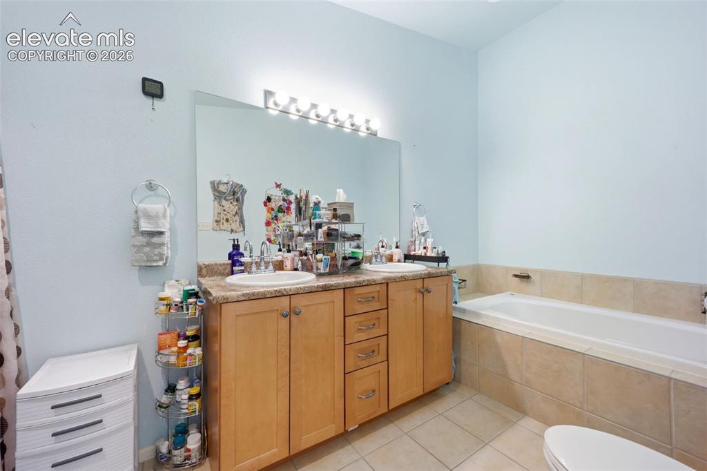 Image 17 of 49: Bathroom featuring a dual vanity with light wood cabinetry, a built-in bath