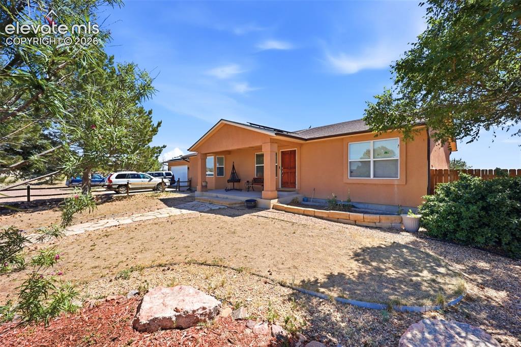 Image 2 of 49: Southwestern-style stucco exterior with a covered front porch and a wood-pa