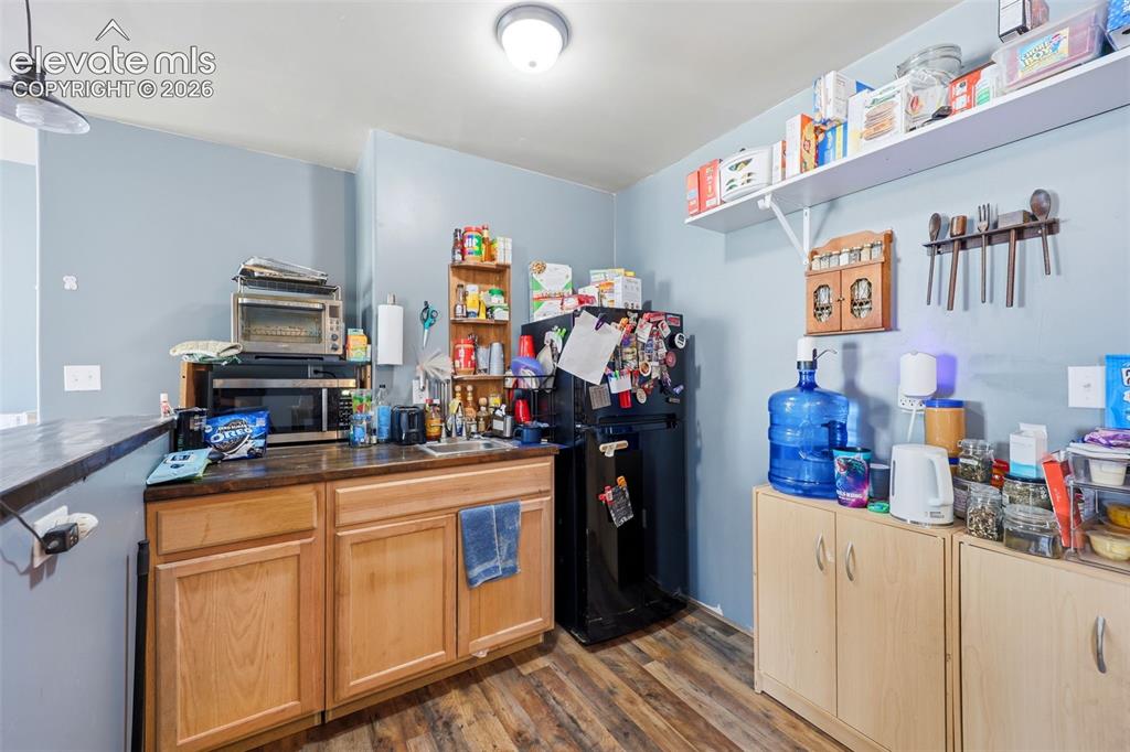 Image 27 of 49: Kitchen area featuring wood-finish flooring, light blue walls, wood cabinet