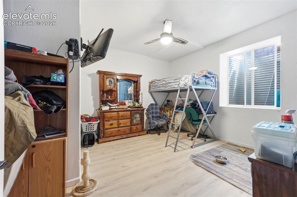 Image 28 of 49: Spacious room featuring light wood-finish flooring, a ceiling fan, and a bu
