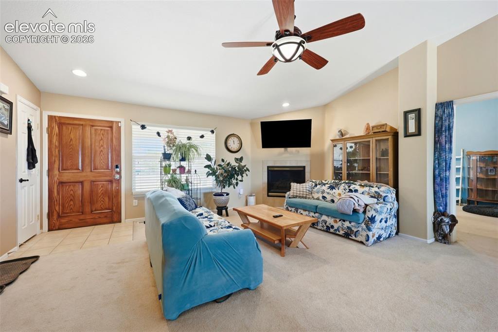 Image 3 of 49: Spacious living area featuring a vaulted ceiling and ceiling fan with integ
