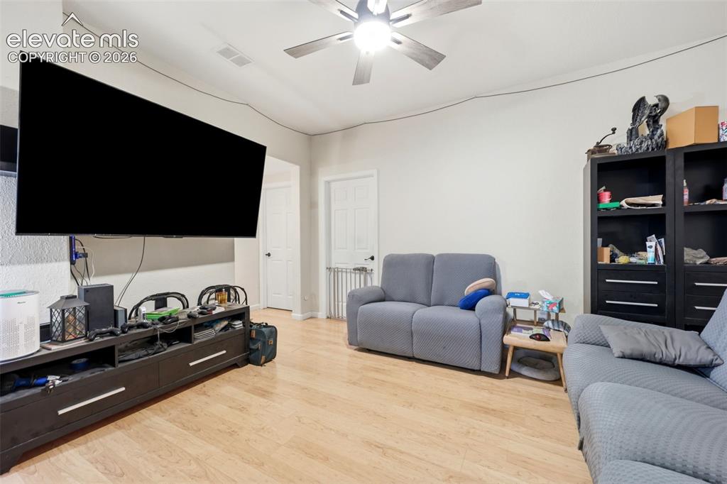 Image 32 of 49: Living area with light wood-finish flooring, light gray walls, and a ceilin