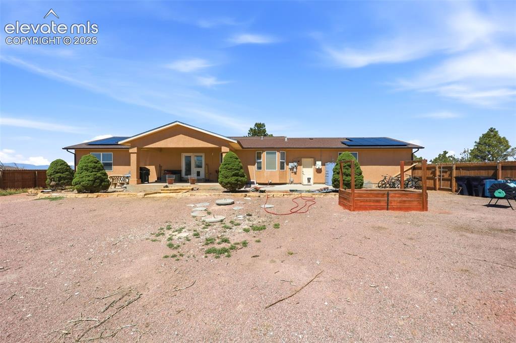 Image 35 of 49: South-facing stucco exterior with a covered patio and multiple solar panels
