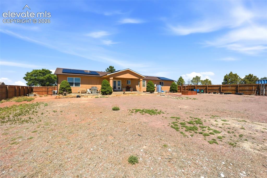 Image 38 of 49: Exterior stucco residence featuring an expansive lot, a covered patio, and