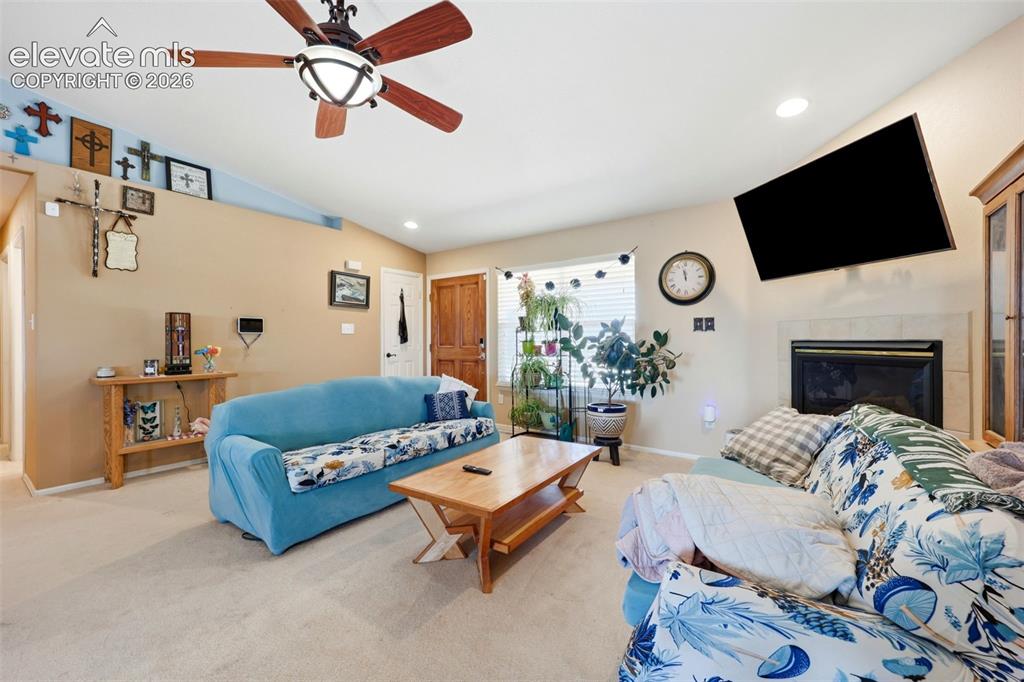 Image 4 of 49: Living area featuring a vaulted ceiling with a ceiling fan