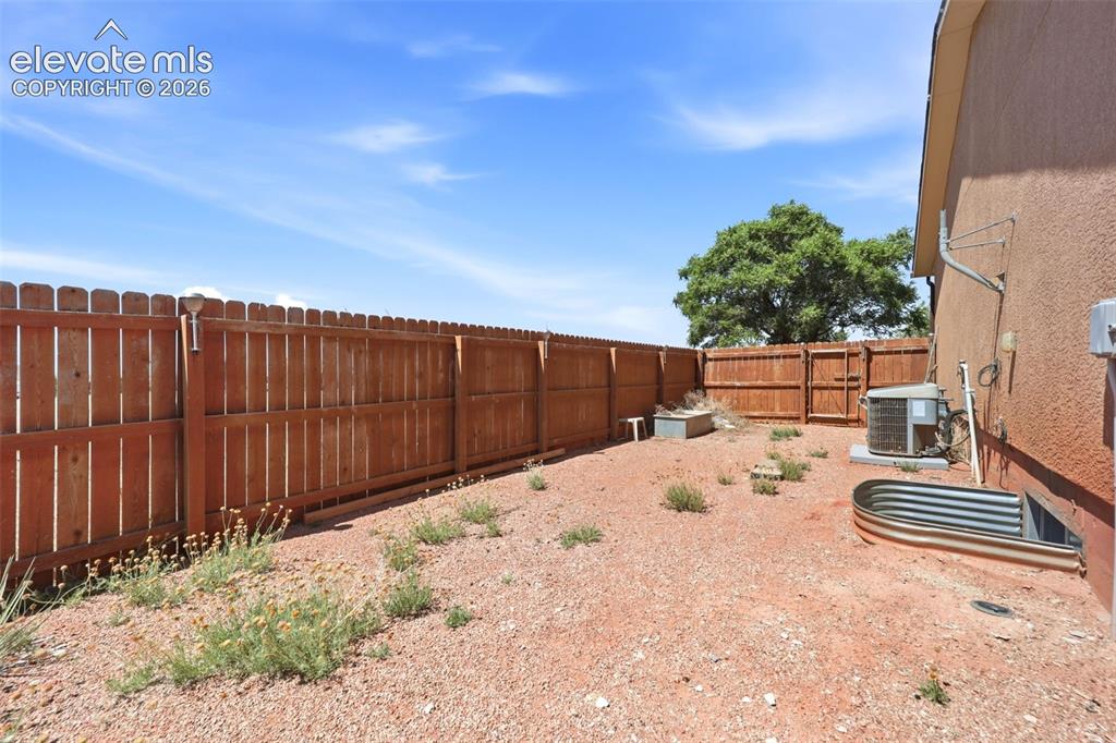 Image 40 of 49: Enclosed backyard space featuring a wood privacy fence and a stucco exterio