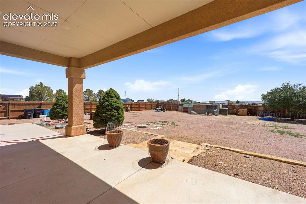 Image 41 of 49: Covered patio with a concrete slab, supporting column, and expansive open y
