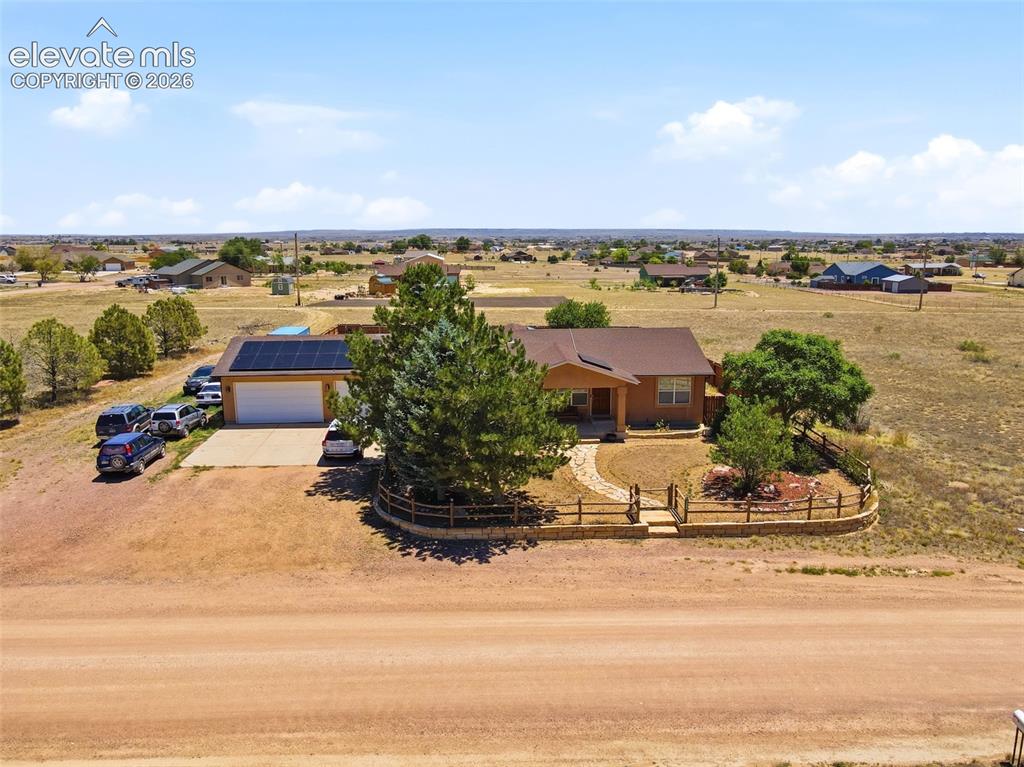 Image 42 of 49: Ranch-style residence featuring a prominent solar panel array, attached gar