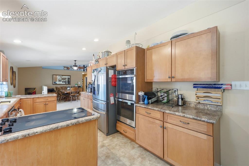 Image 7 of 49: Kitchen featuring light wood cabinetry, stone-look countertops, stainless s