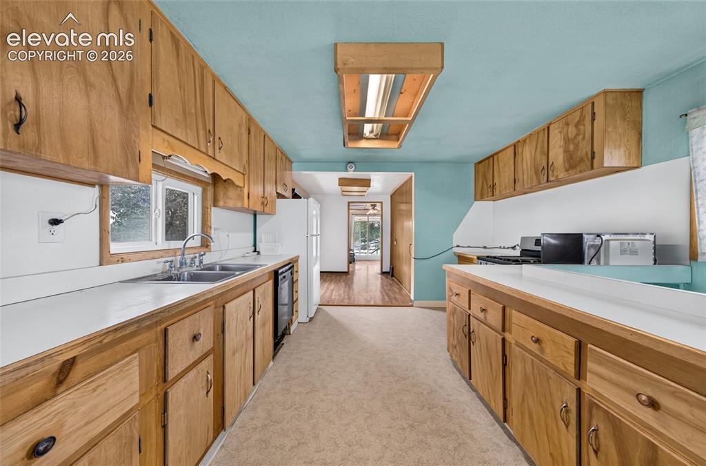 Image 12 of 45: Galley kitchen featuring wood cabinetry, white countertops, a double basin