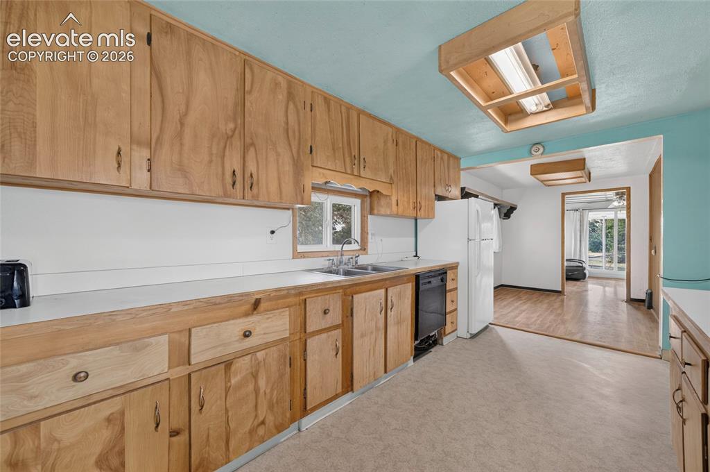 Image 14 of 45: Wood cabinetry throughout, built-in dishwasher, and a double basin sink