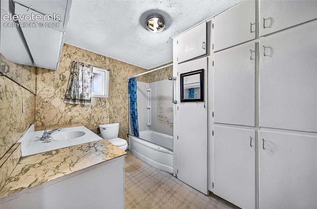 Image 16 of 45: Built-in white cabinetry, full bathtub with shower, wall-mounted sink, and 