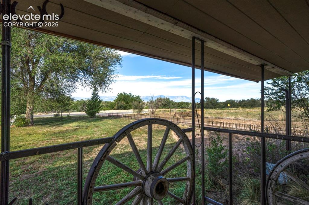 Image 2 of 45: View from covered porch with decorative wrought iron railing, wagon wheel a