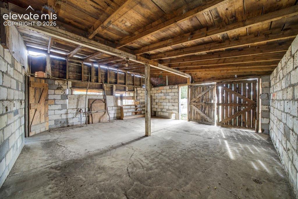 Image 35 of 45: Concrete flooring, exposed wood beam ceiling, block wall construction, wood