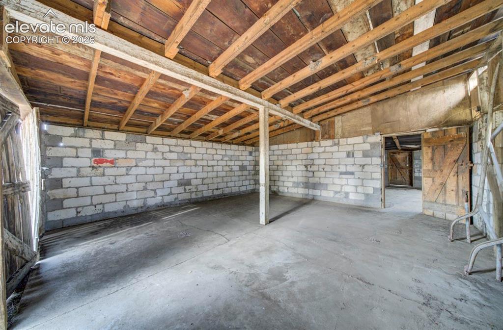 Image 36 of 45: Exposed wood-beam ceiling with wood planking, concrete flooring, and white 