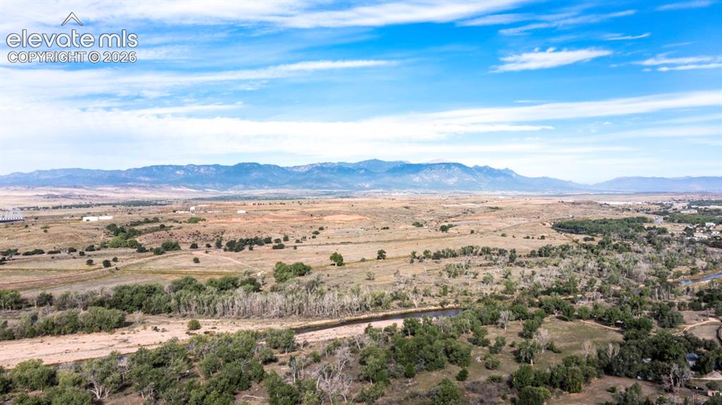Image 40 of 45: Expansive landscape with a winding river, mature tree lines, and distant mo