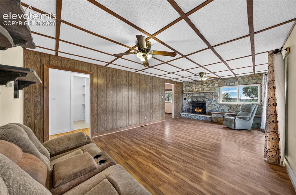 Image 5 of 45: Large living room with paneling and a stone-clad fireplace