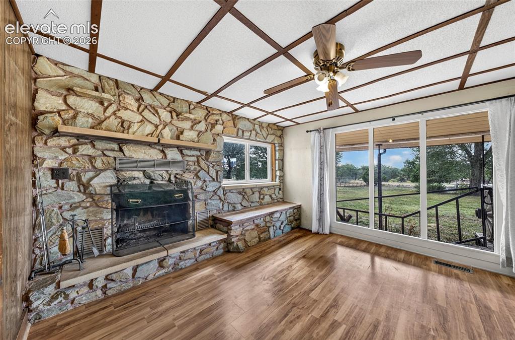 Image 8 of 45: Stone-clad fireplace with hearth seating, and ceiling fans