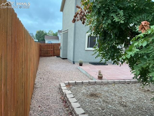Image 7 of 29: Left of home looking towards street Fenced backyard with a patio