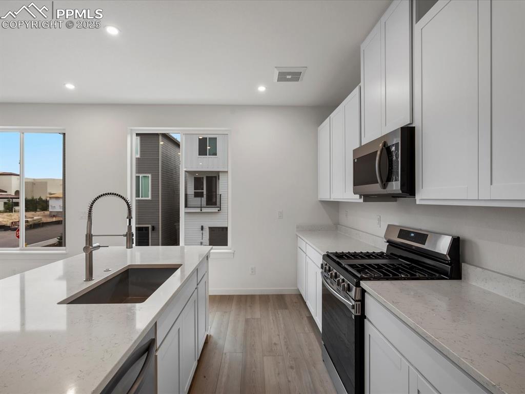 Image 10 of 32: Kitchen with stainless steel appliances, light wood-style flooring, light s