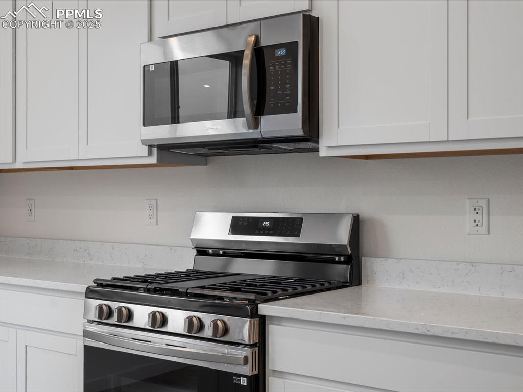 Image 12 of 32: Kitchen with appliances with stainless steel finishes, white cabinets, and 