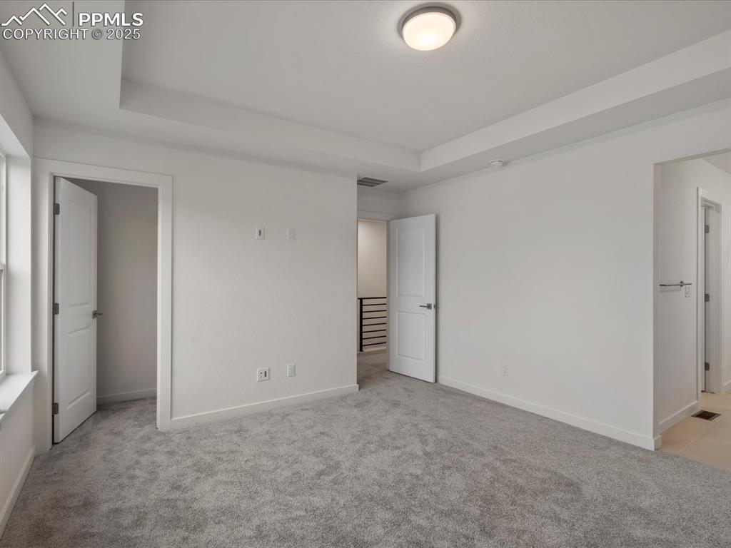 Image 17 of 32: Unfurnished bedroom with light carpet and a raised ceiling