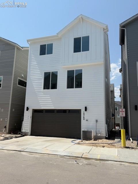 Image 2 of 32: Rear view of property with an attached garage, board and batten siding, and