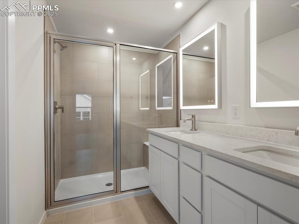 Image 20 of 32: Bathroom featuring double vanity, a stall shower, tile patterned flooring, 