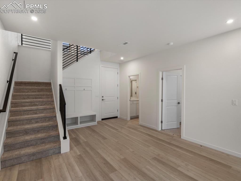 Image 7 of 32: Unfurnished living room featuring stairway, light wood-type flooring, and r
