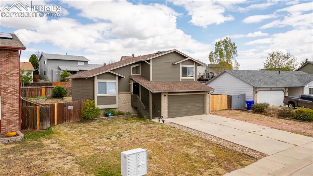 Image 3 of 49: Split-level residence featuring a two-car garage with a brown door, light g