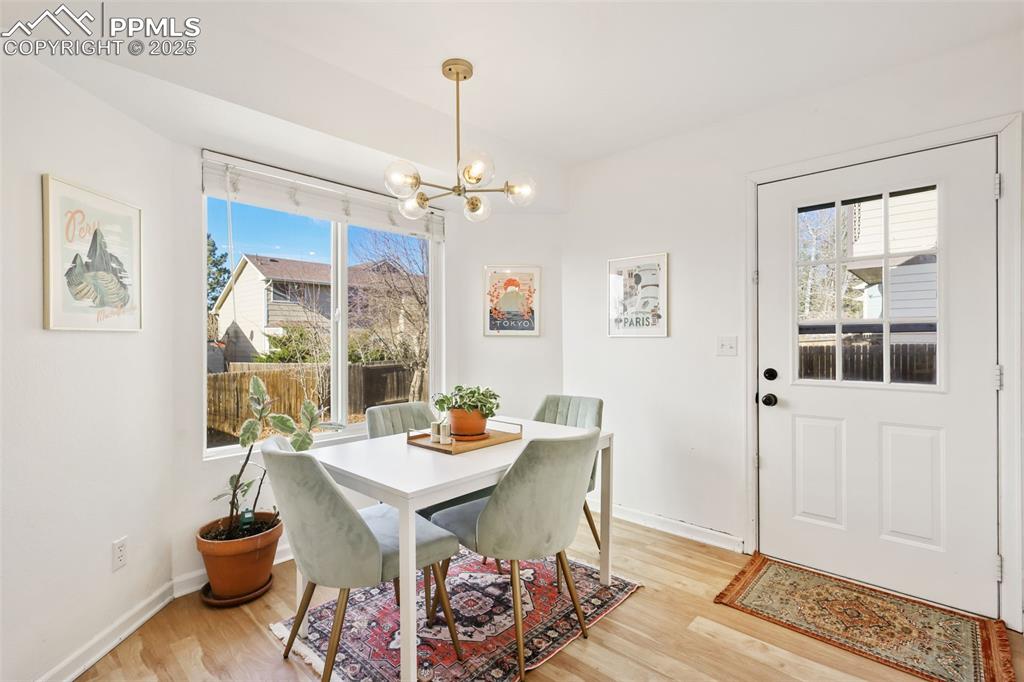Image 11 of 27: Dining space with light wood finished floors, healthy amount of natural lig