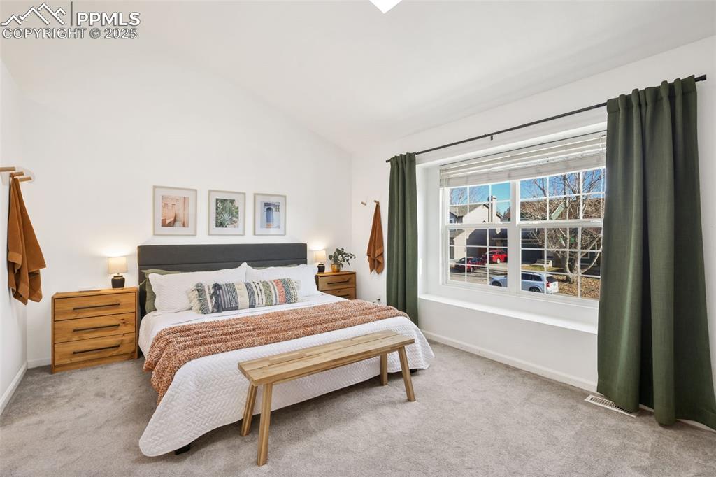 Image 13 of 27: Bedroom featuring vaulted ceiling and light carpet