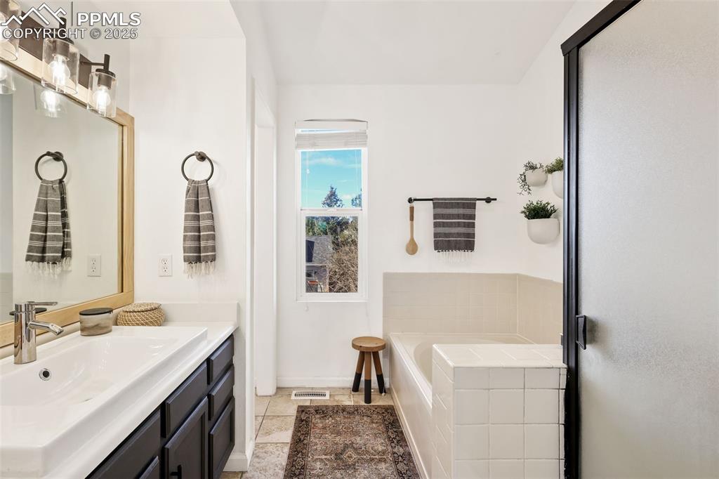 Image 15 of 27: Bathroom with a garden tub, vanity, and a shower stall
