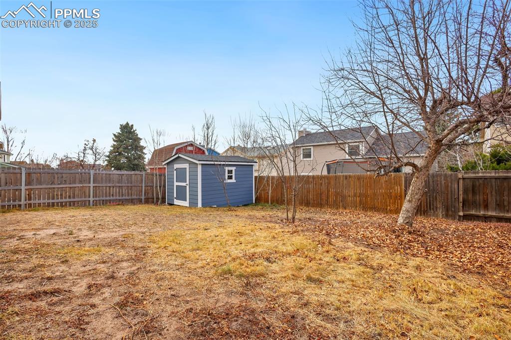 Image 25 of 27: Fenced backyard with a storage unit
