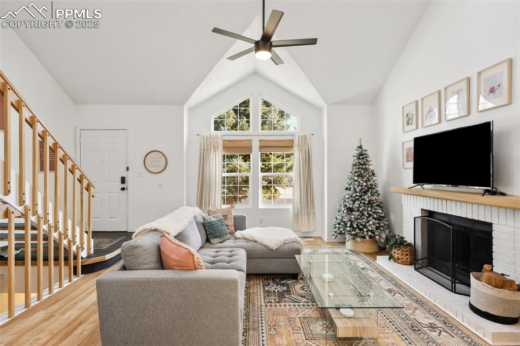 Image 3 of 27: Living room with wood finished floors, lofted ceiling, a brick fireplace, s