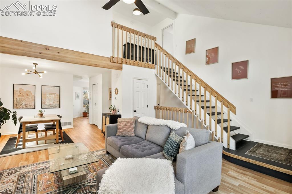 Image 5 of 27: Living room with light wood finished floors, beam ceiling, a chandelier, st