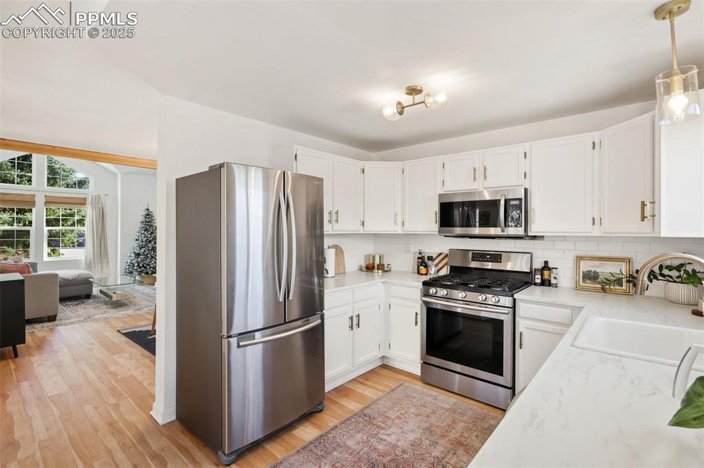Image 8 of 27: Kitchen featuring appliances with stainless steel finishes, white cabinetry