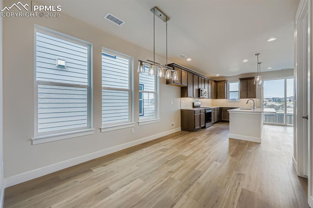 Image 10 of 28: Kitchen featuring decorative light fixtures, light wood-type flooring, stai